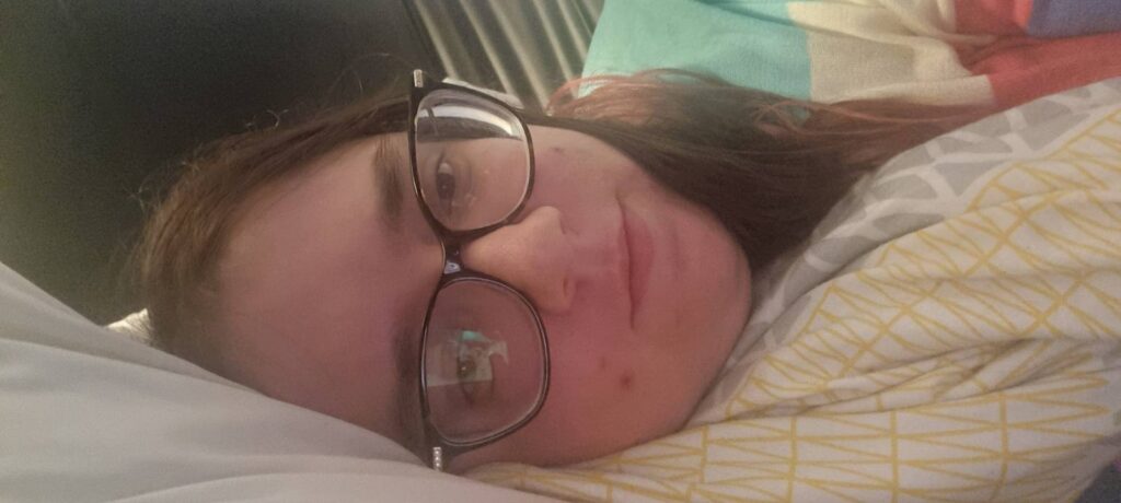 Laura Ann Moulding laying down wrapped in a yellow patterned duvet.